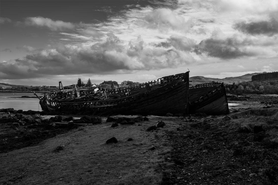 A wrecked boat on the shore in black and white