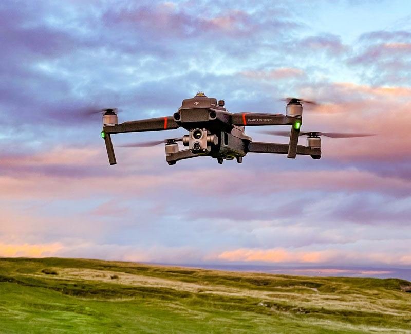 A drone in flight above moorland at dusk
