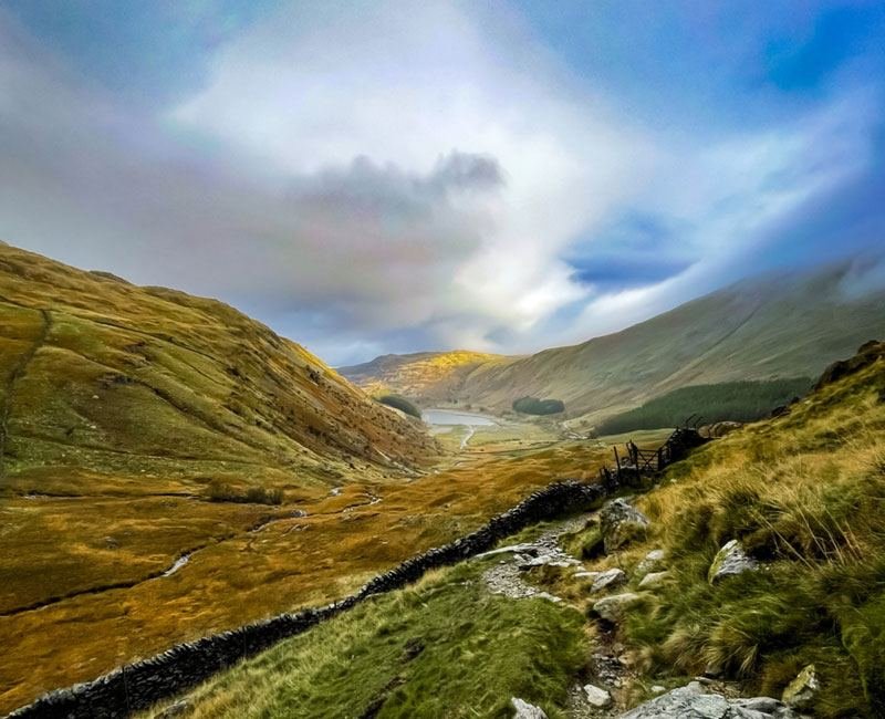 A green fell valley under broken cloud